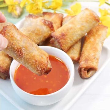 Dipping egg roll into sweet chili sauce.