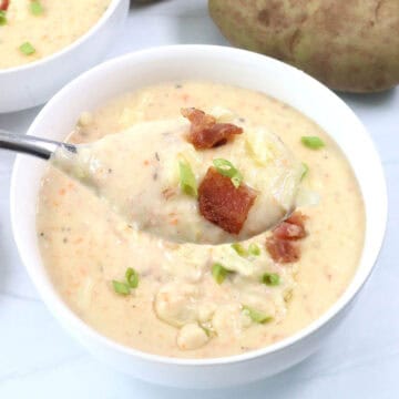 Spoonful of Baked Potato Soup with garnish.