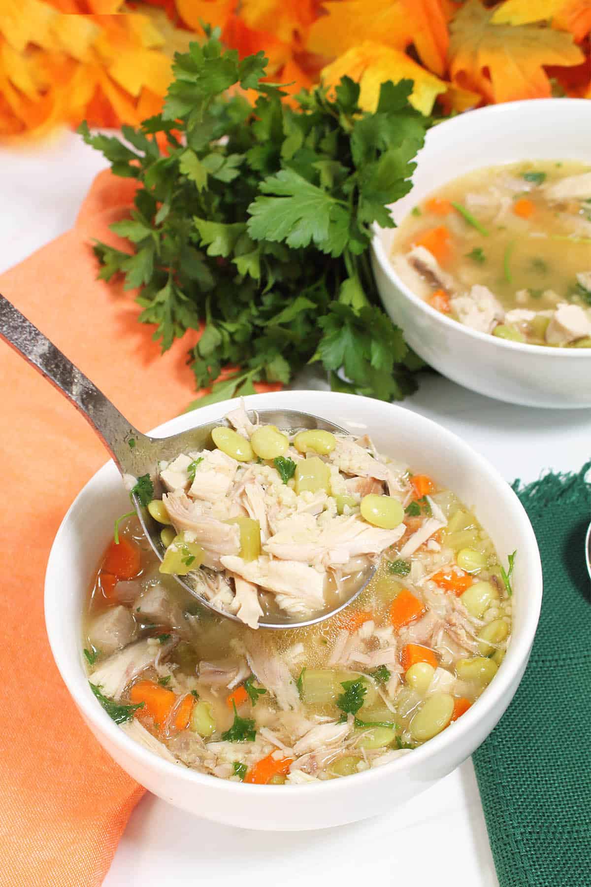 Ladling soup into bowls on peach and green napkins.