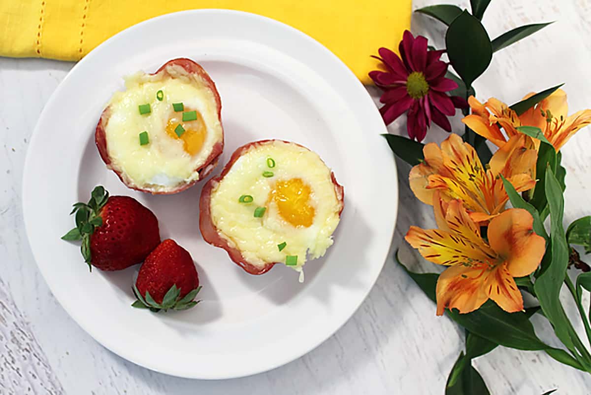 Overhead of two egg cups on white plate with flowers.