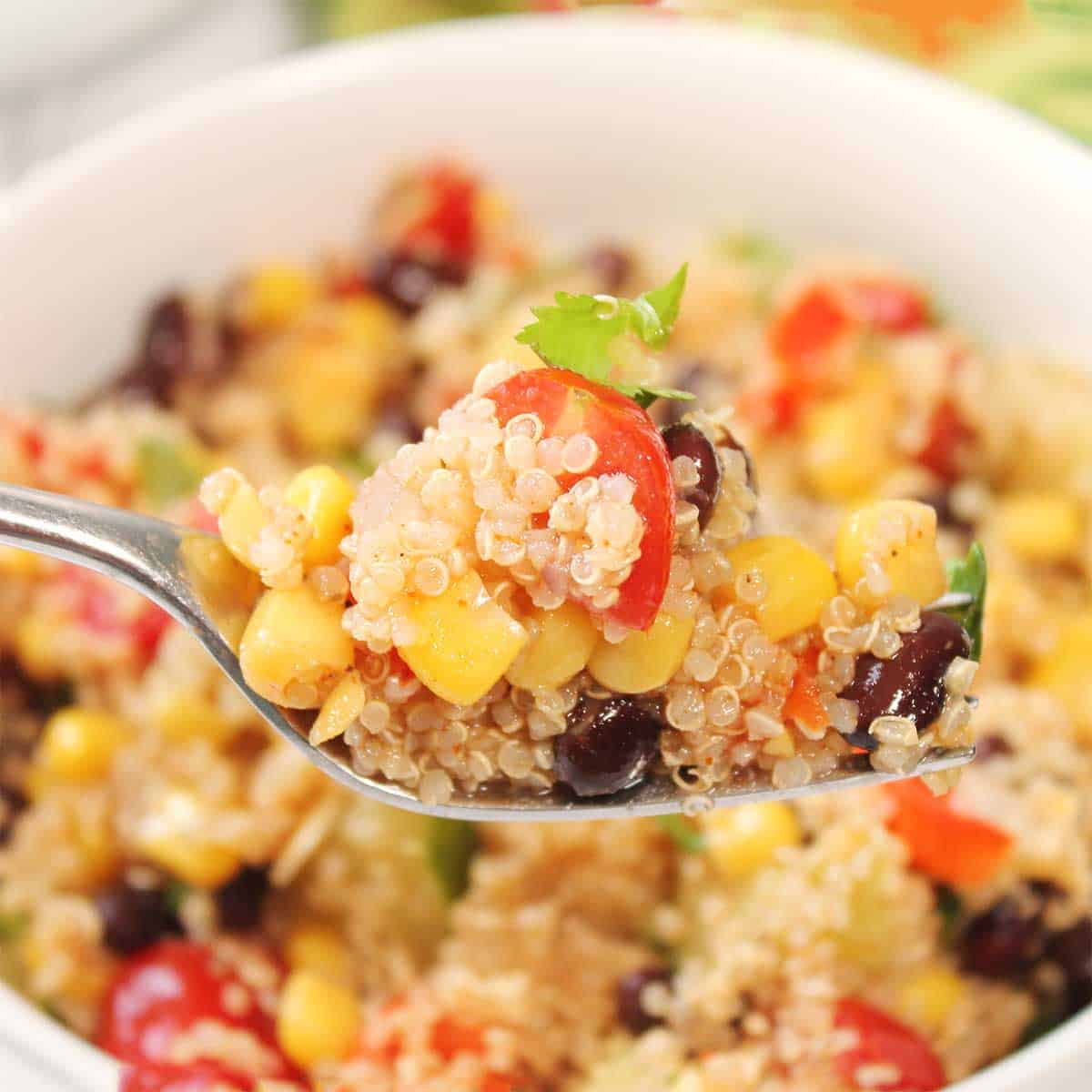 Forkful of quinoa and black bean salad over bowl.