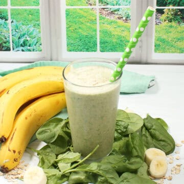 Spinach Banana Smoothie with straw by window,