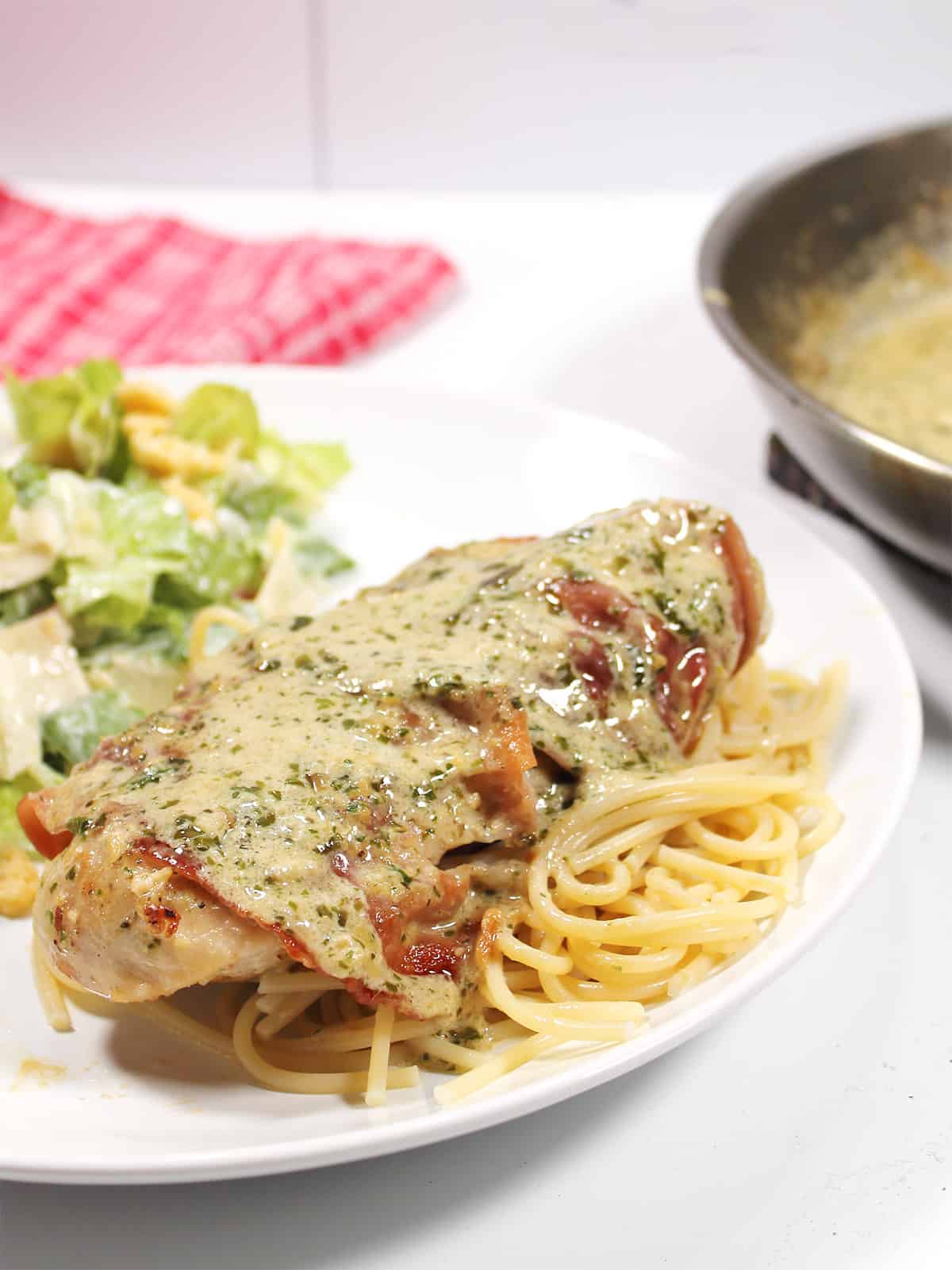 Closeup of chicken covered in basil pesto cream sauce.