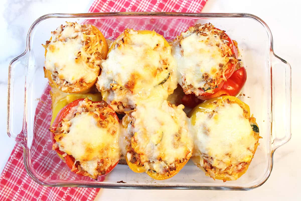 Overhead of baked peppers stuffed with orzo and ground beef.