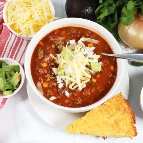 Spicy Crockpot Chili in bowl with garnishes around it.