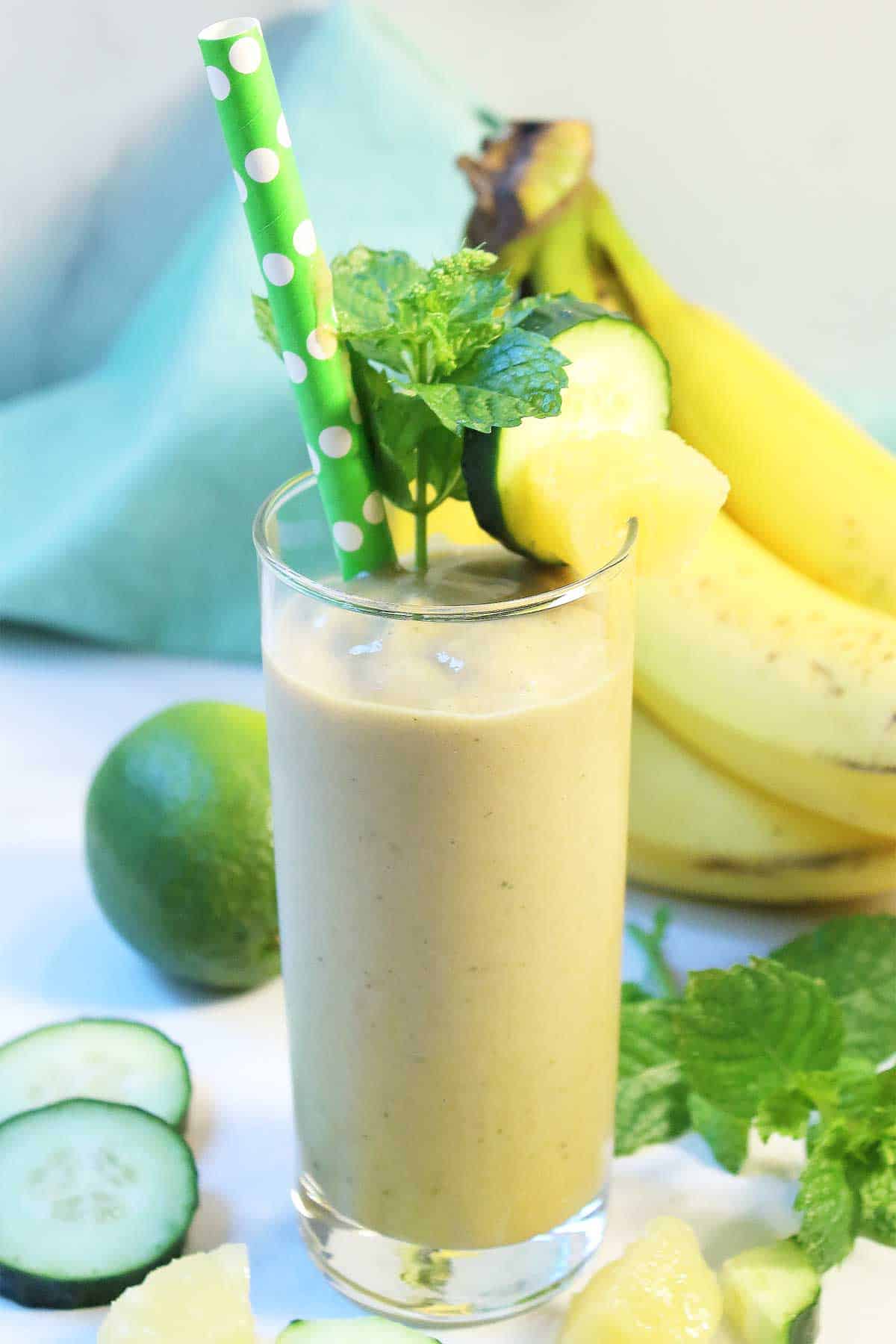 Banana Pineapple Smoothie with cucumber, pineapple and bananas around it.