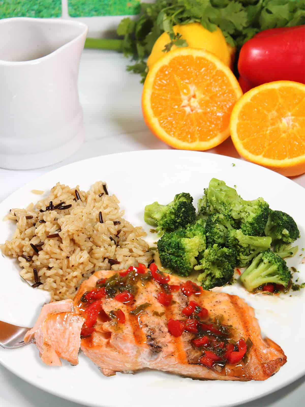 Plated grilled salmon dinner with bite of orange salmon on fork.