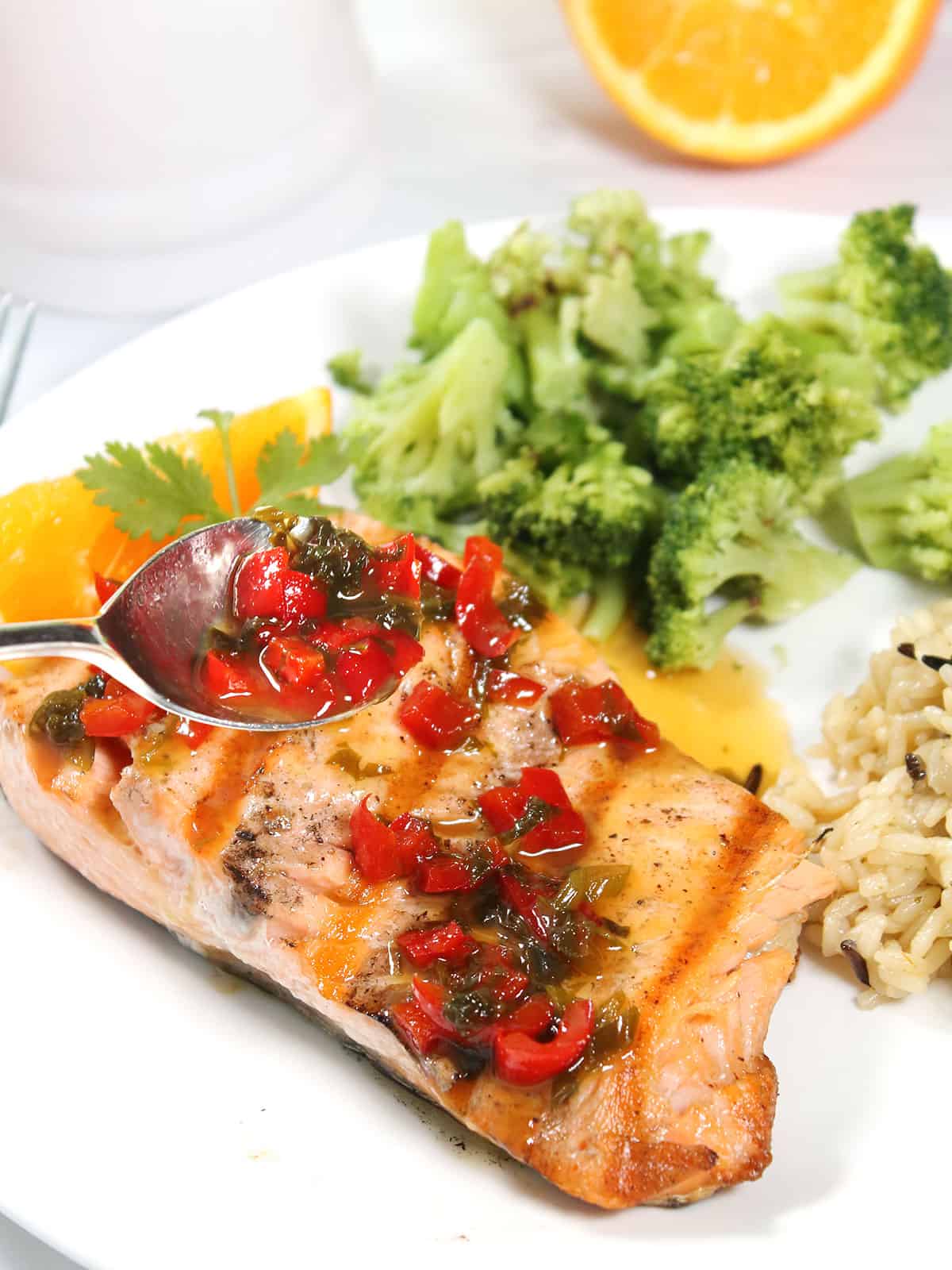 Spooning orange sauce over grilled orange salmon.