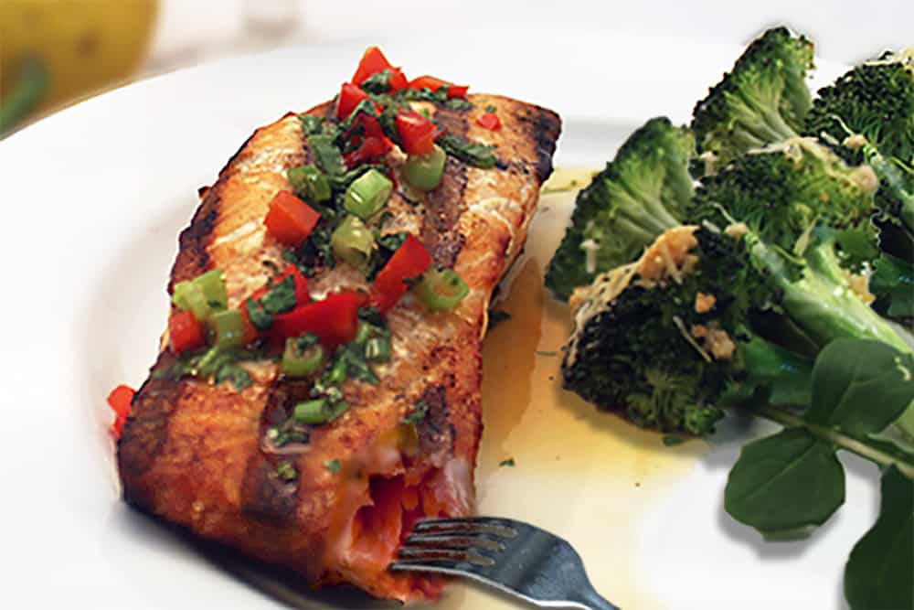 Showing inside of pink flaky salmon with broccoli.