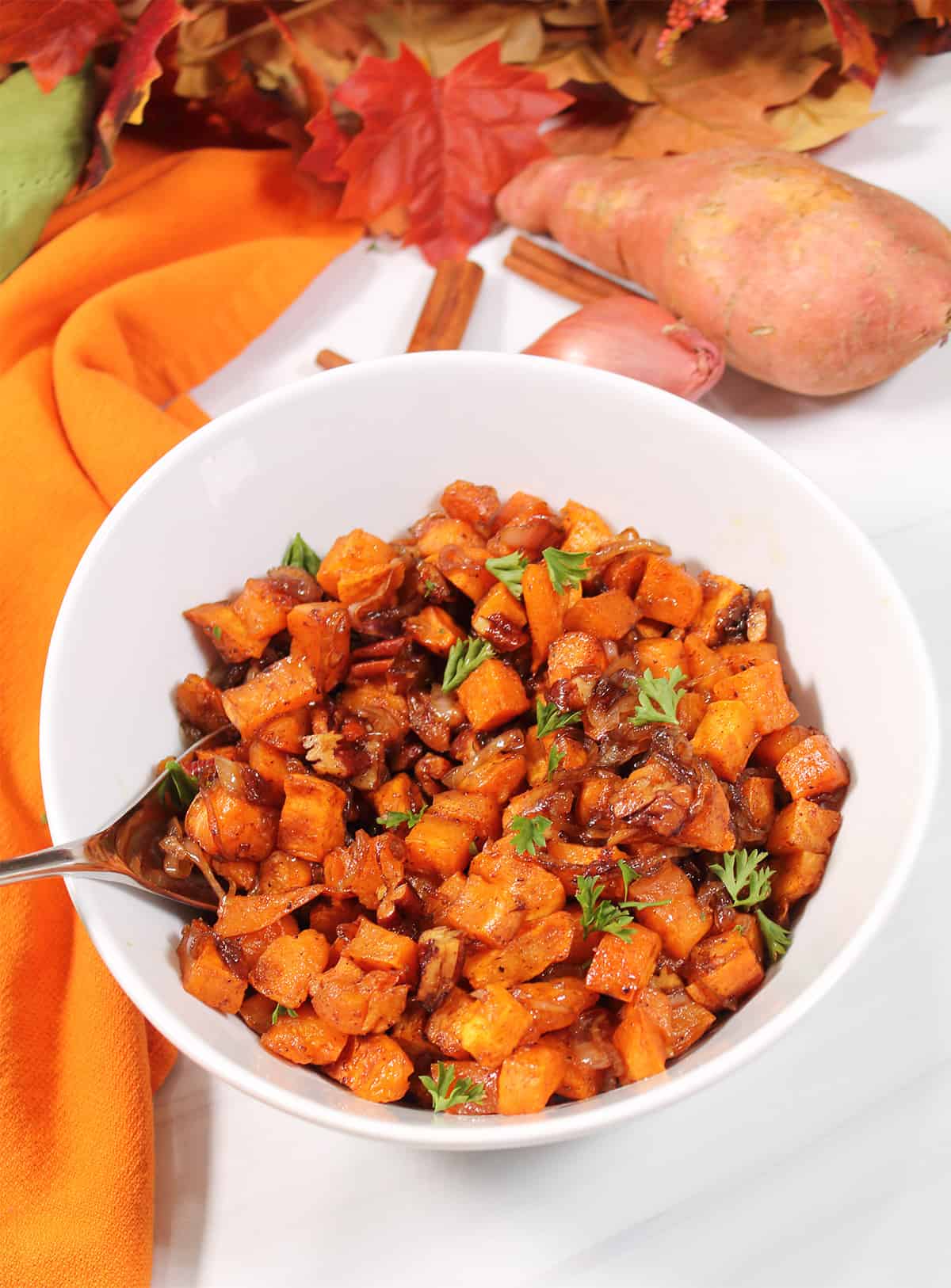 Roasted sweet potatoes in bowl with parsley garnish.