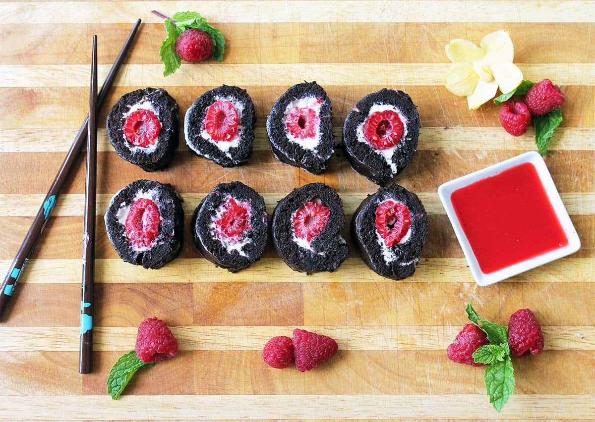 Overhead of sliced raspberry dessert on wooden board.