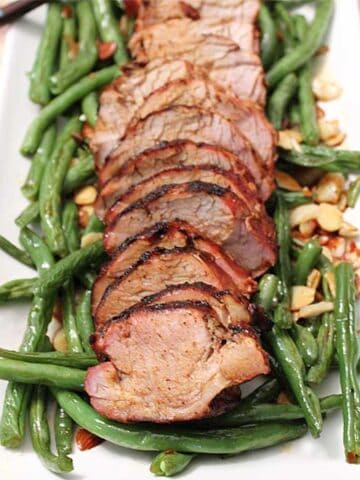 Asian Grilled Pork Loin on white platter with green beans.