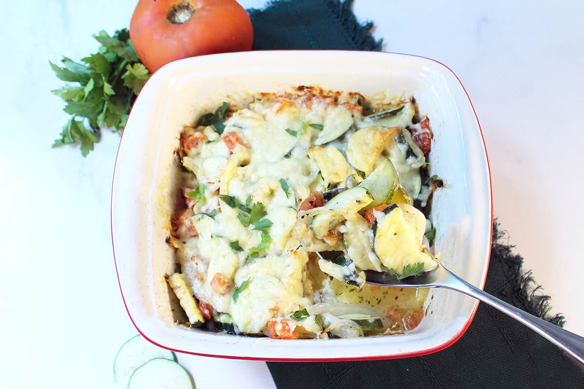 Overhead of cooked casserole with serving spoon in it on green napkin.