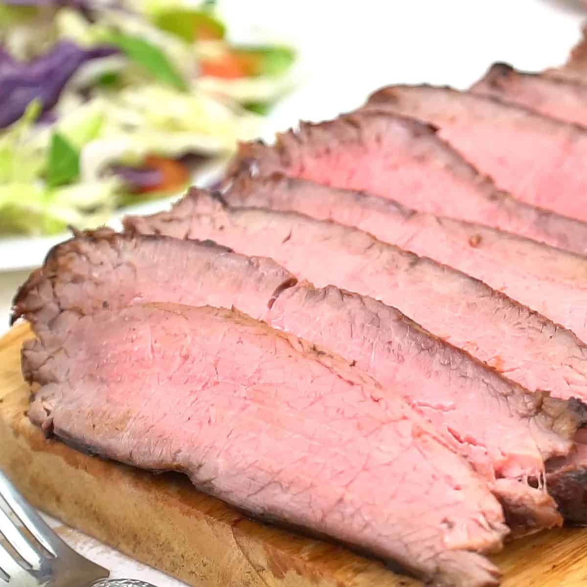 Closeup of sliced flank steak on cutting board.