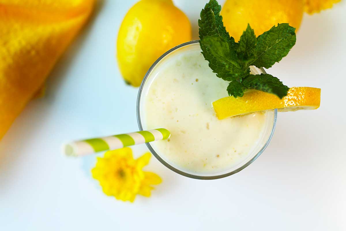 Overhead of lemon banana smoothie with straw and mint garnish.