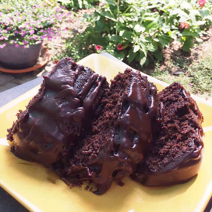 Three slices of pound cake on yellow plate in garden.