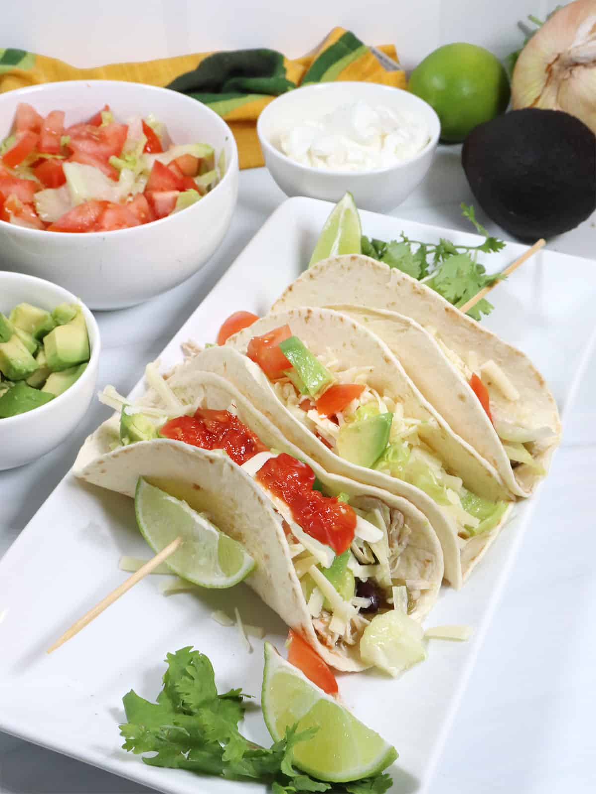 3 chicken tacos skewered with lime wedges.