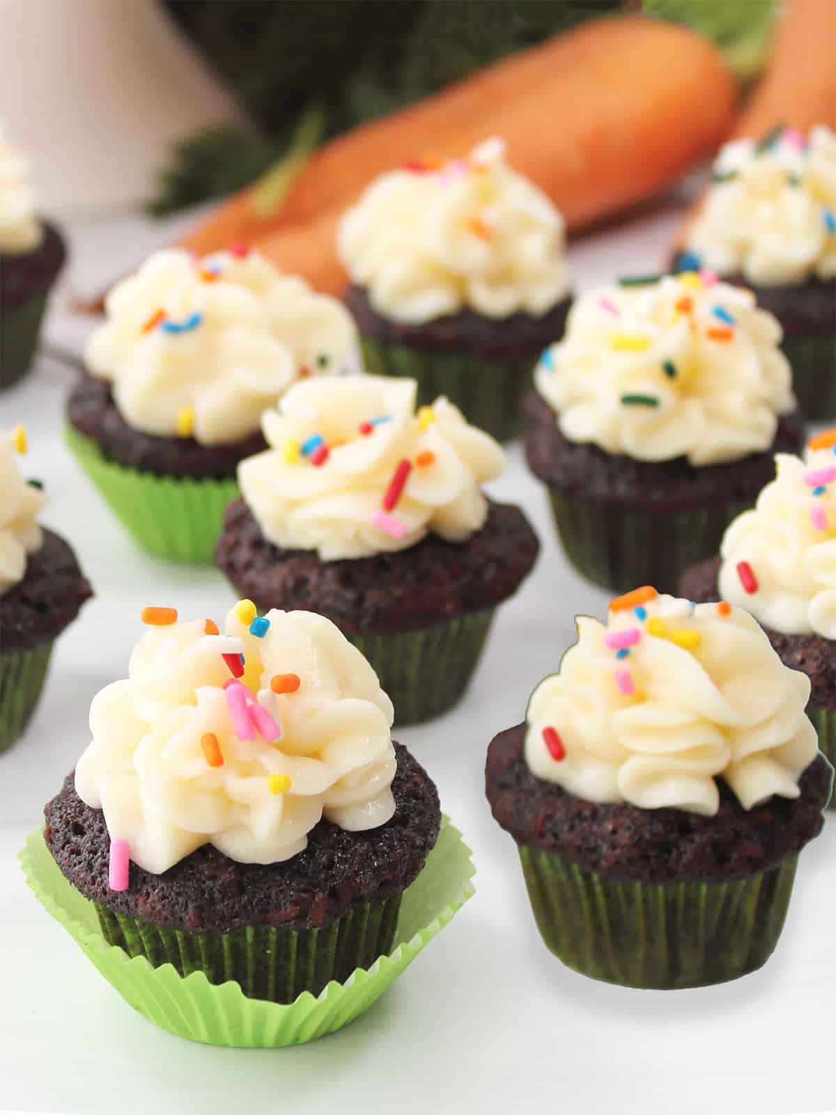 Mini chocolate carrot cake cupcakes scattered on table.