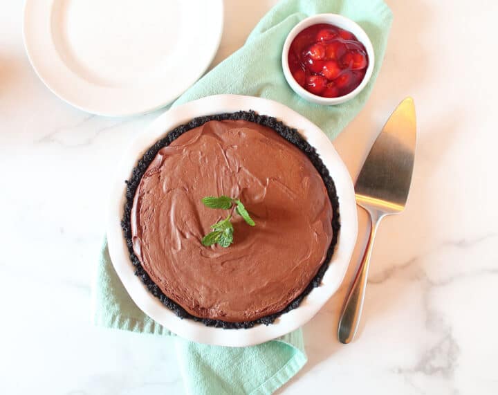 Overhead of no bake chocolate pie with sprig of mint on top and green napkin underneath.