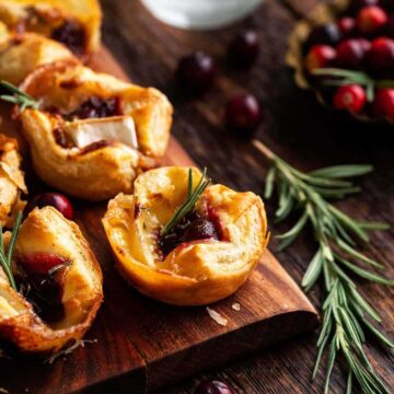 Cranberry Brie Bites with puff pastry on wooden board.