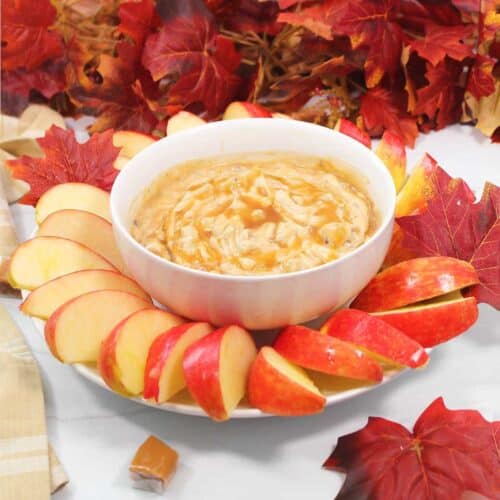 Cream cheese caramel apple dip surrounded by apple slices.