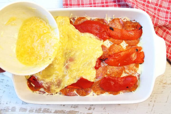 Pouring egg mixture over all layers in casserole.
