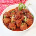 Cranberry meatballs in white bowl with toothpicks.