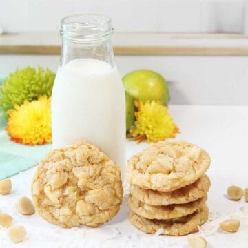 Key Lime White Chocolate cookies stacked and leaning on milk bottle.