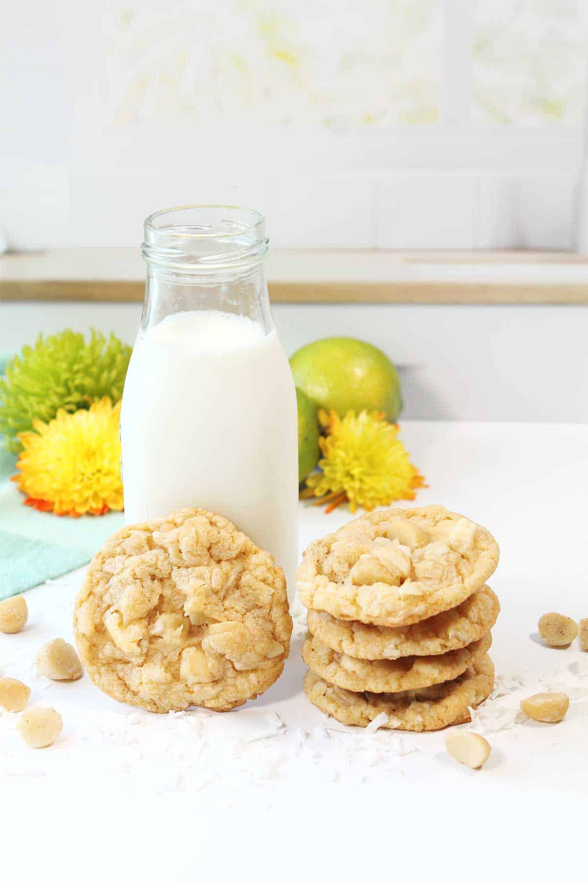 Stacked key lime white chocolate cookies next to milk bottle.