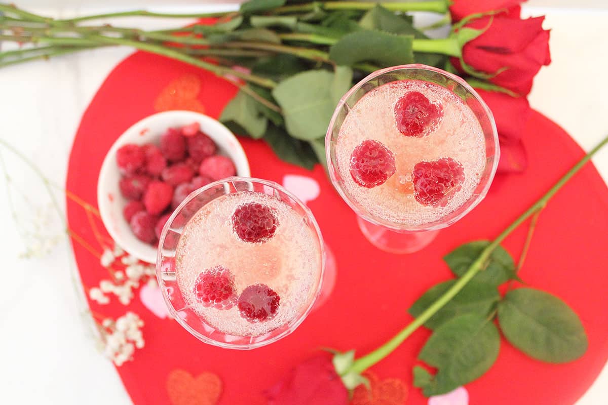Overhead of two white wine cocktails with roses.