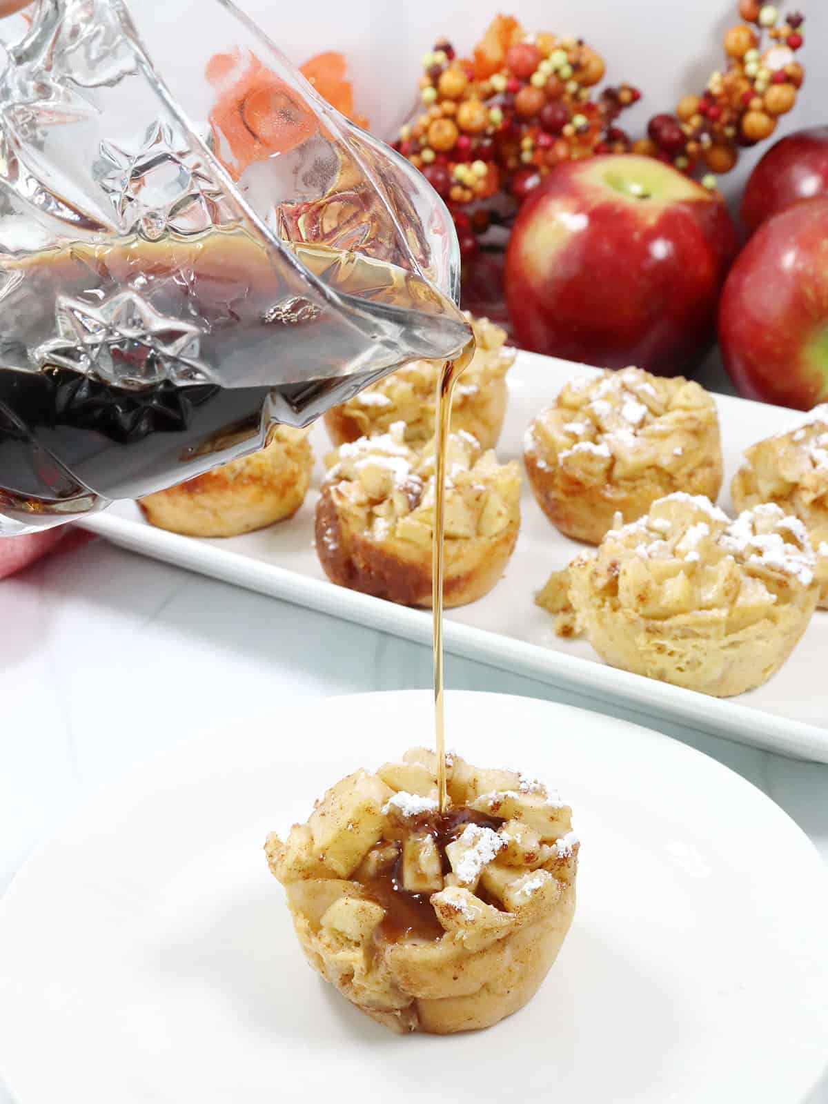 Pouring maple syrup over Apple French Toast muffins.