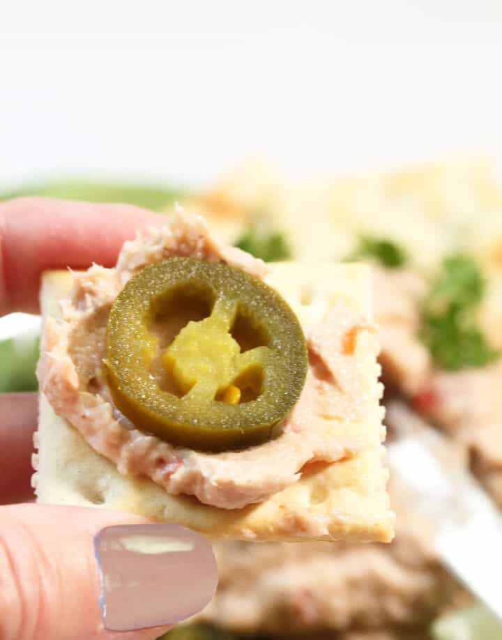 Bite of fish dip on cracker topped with jalapeno.