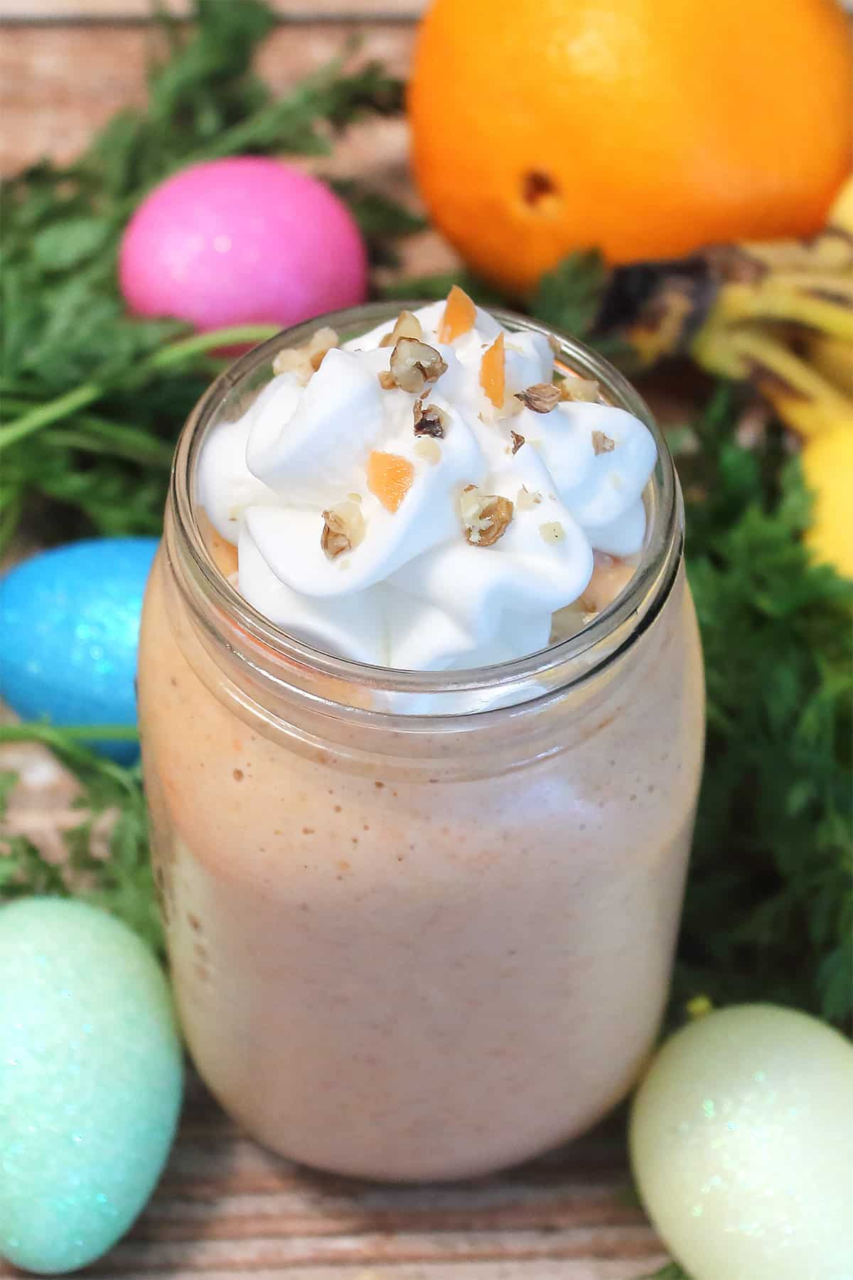 Whipped cream topped carrot cake smoothie with greens and colored eggs.