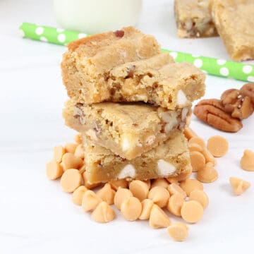 Butterscotch Blondies with bite out stacked on butterscotch chips.