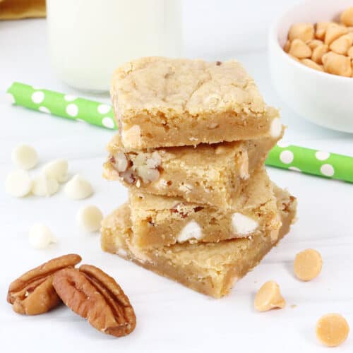 Stacked butterscotch blondies with white chocolate chips and nuts around.
