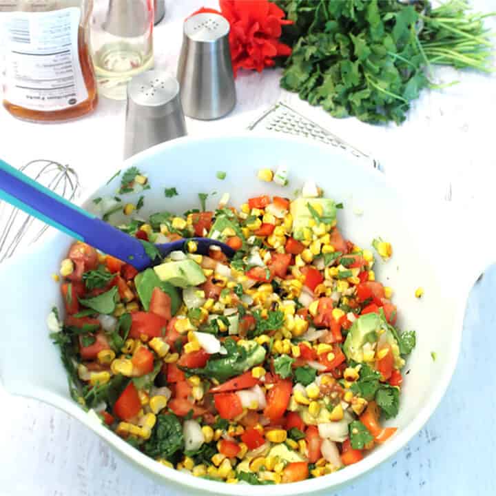 Mixing Corn Salad ingredients in white bowl. 