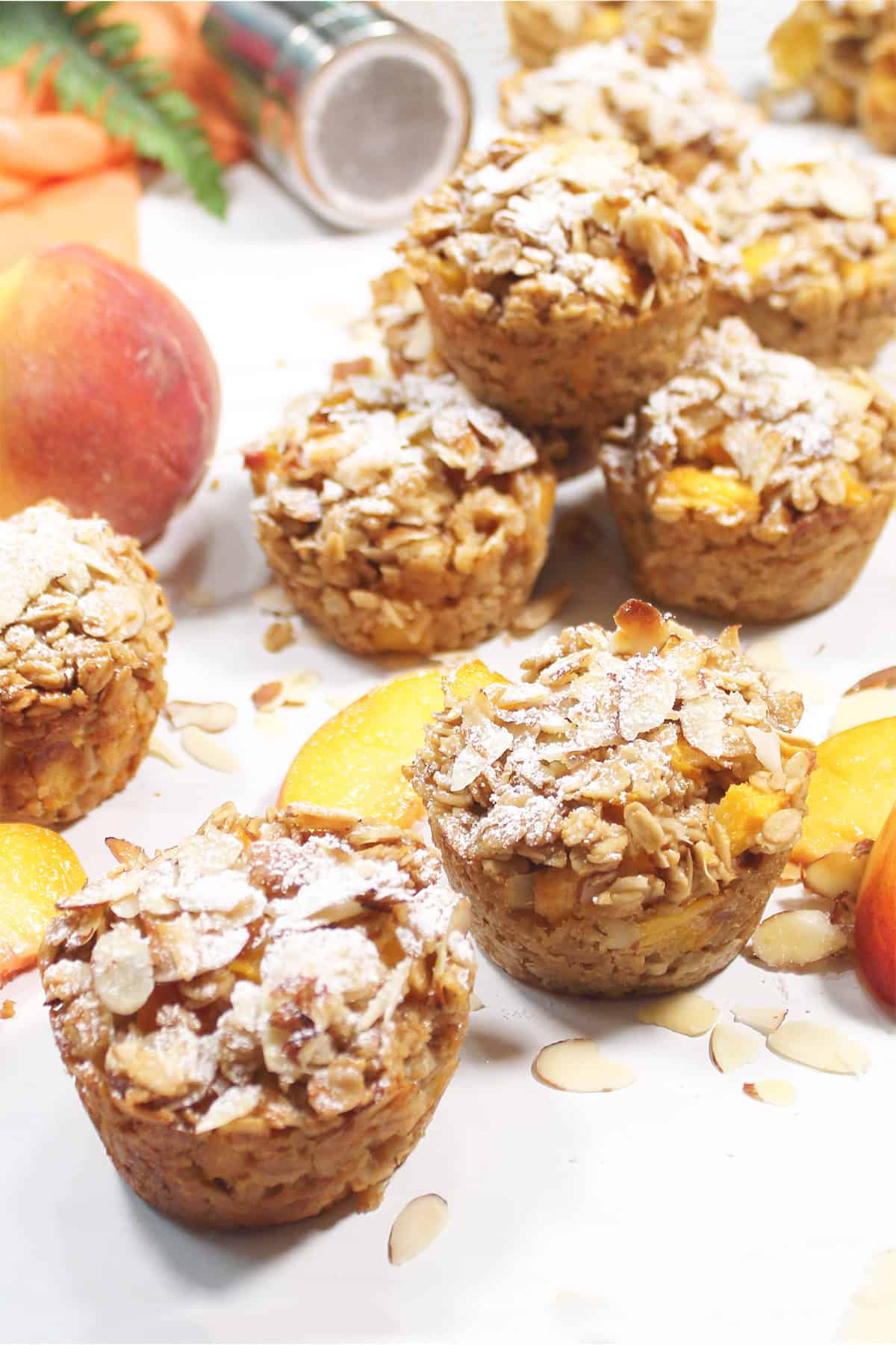 Scattered peach oatmeal muffins on white table.