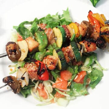 Skewered grilled pork on top of salad.