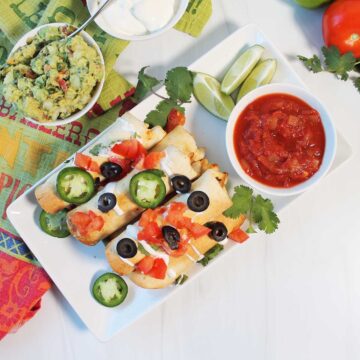 Overhead of air fryer chicken taquitos with sides.