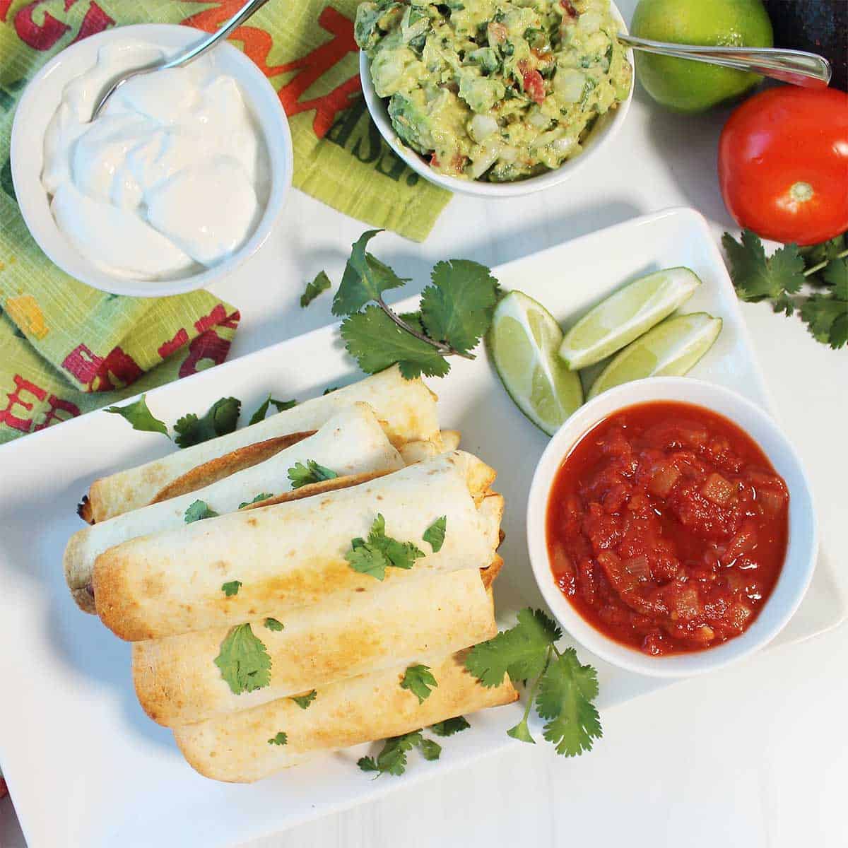 Stacked rotisserie chicken taquitos with cilantro garnish.