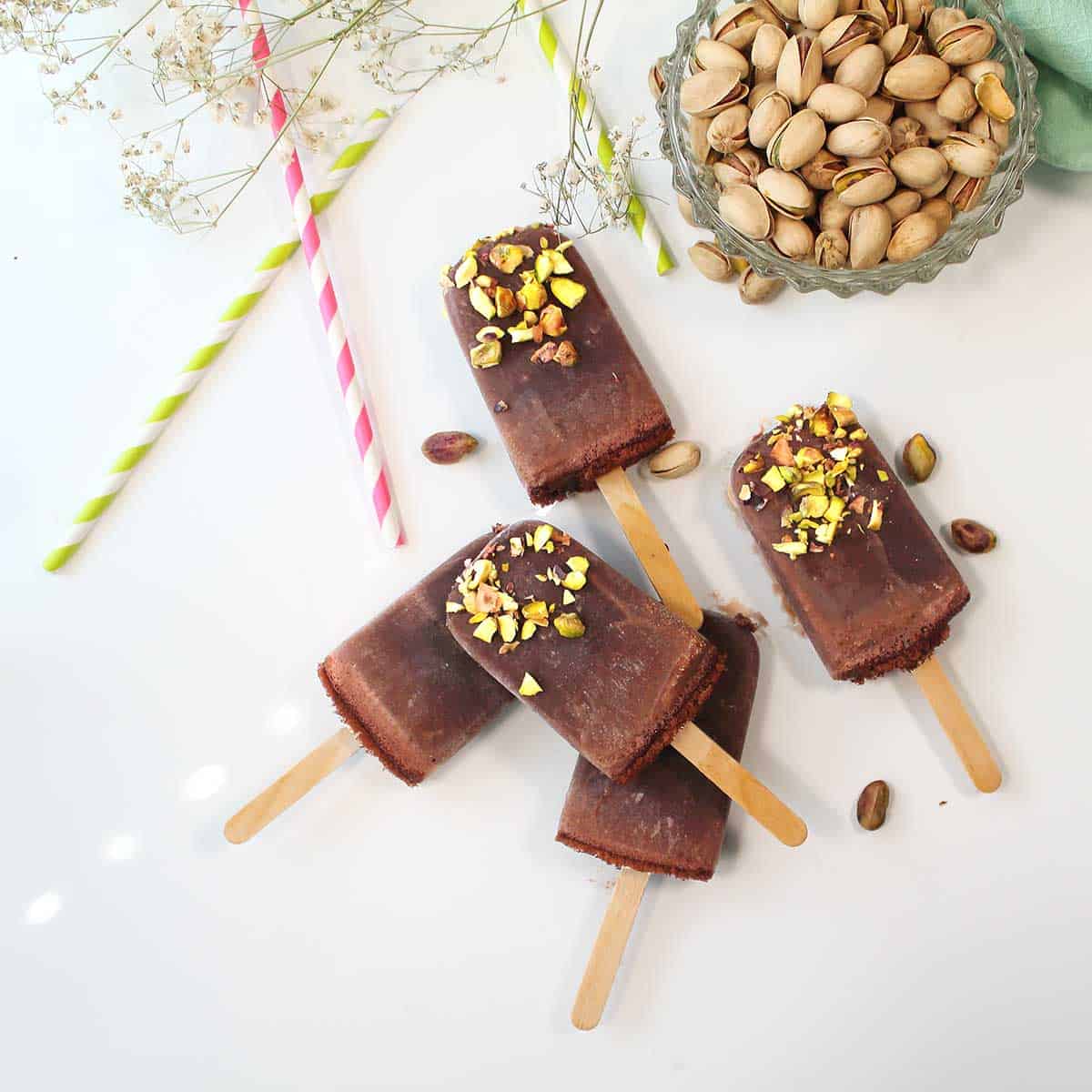 Scattered fudgesicles with nuts and colorful straws.