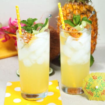 2 Pineapple Coconut Mojito drinks with mint and pineapple garnish,