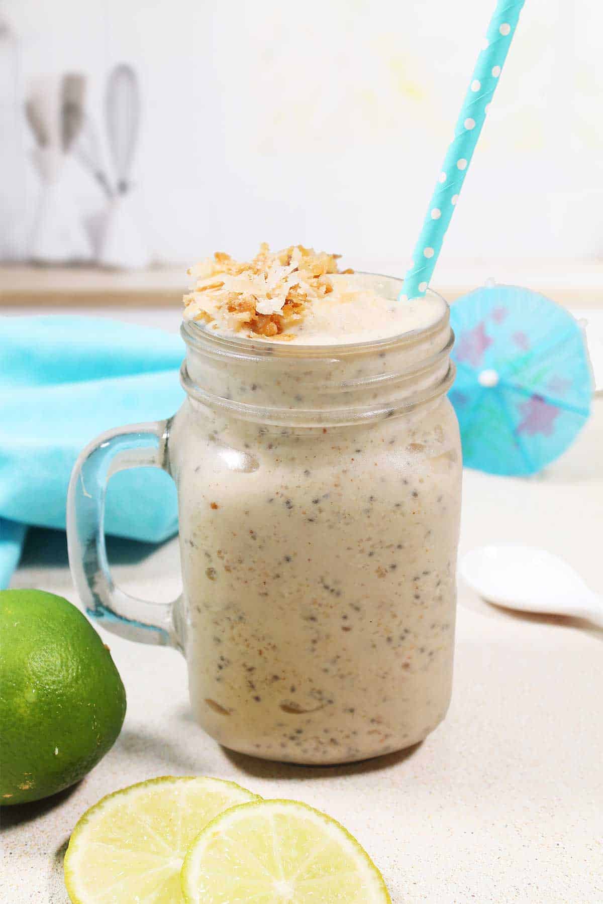Closeup of coconut smoothie in jar with straw.