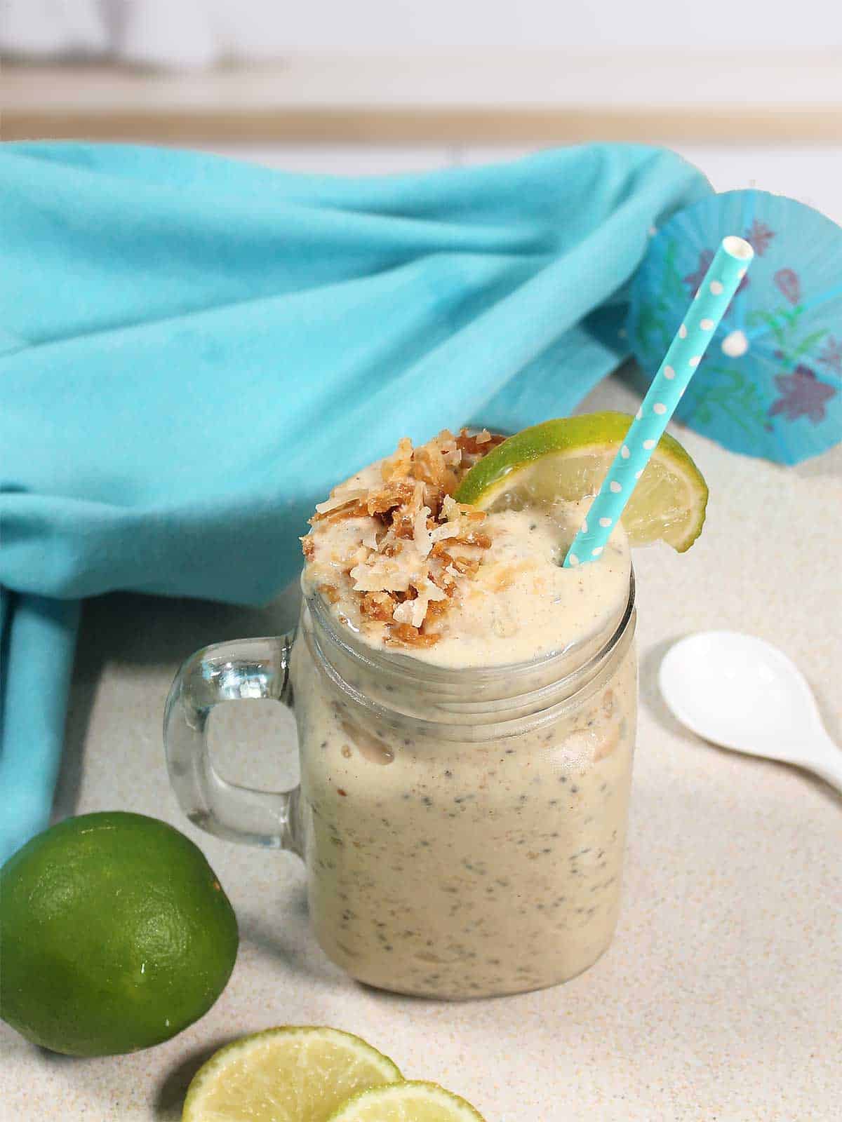 Coconut smoothie garnished with toasted coconut and slice of lime.