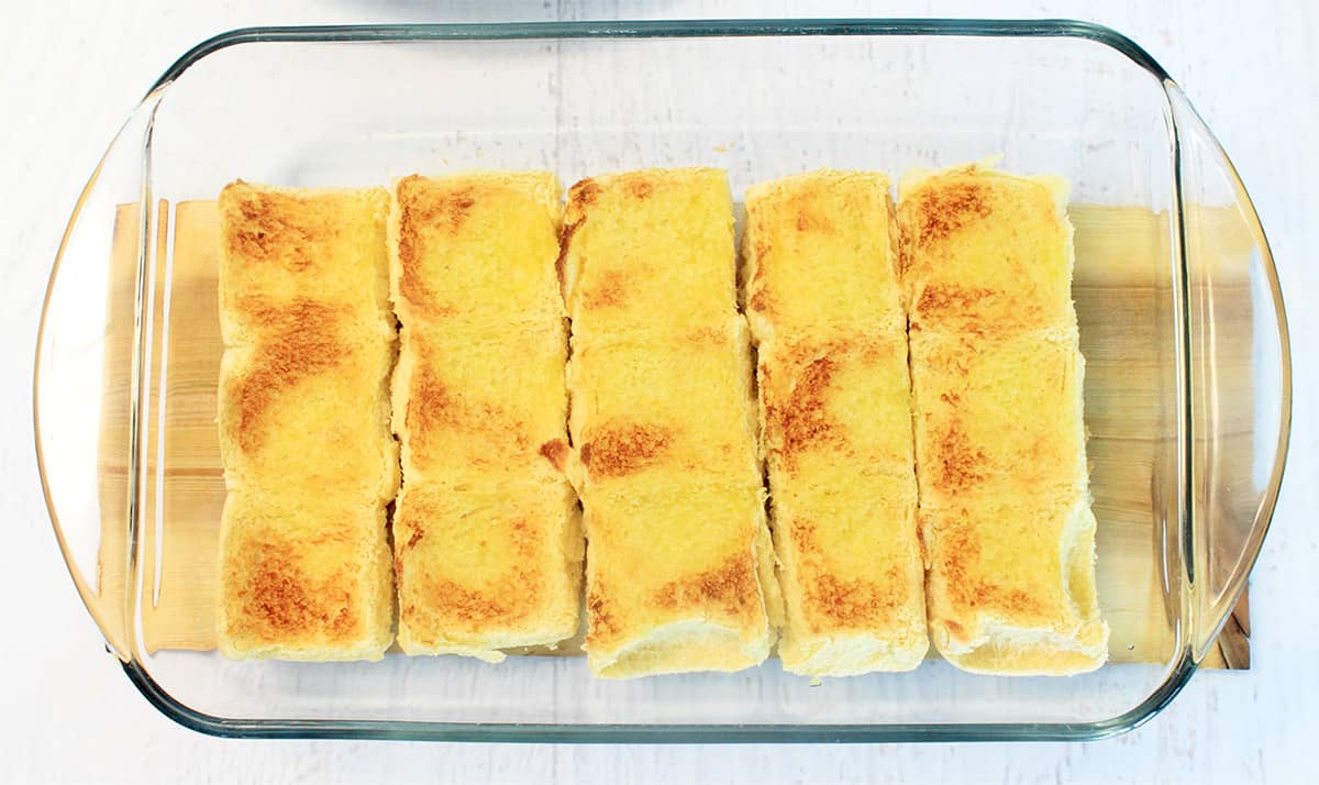 Slider bun in baking dish brushed with oil and browned under broiler.