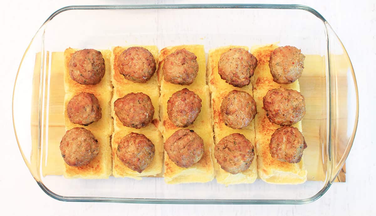 Meatballs atop browned slider buns.
