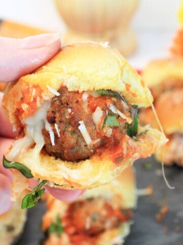 Holding a meatball slider over tray.