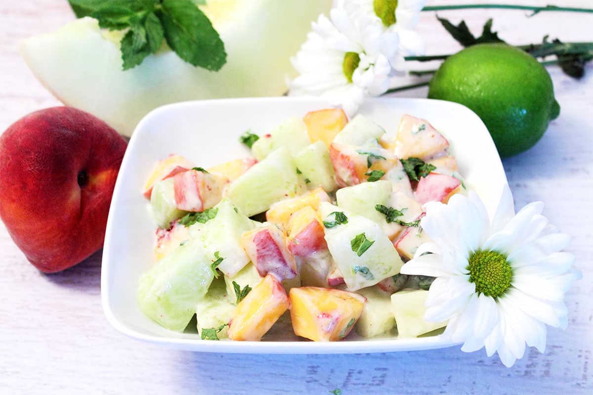 Honeydew Salad with peaches, melon and daisies around it.