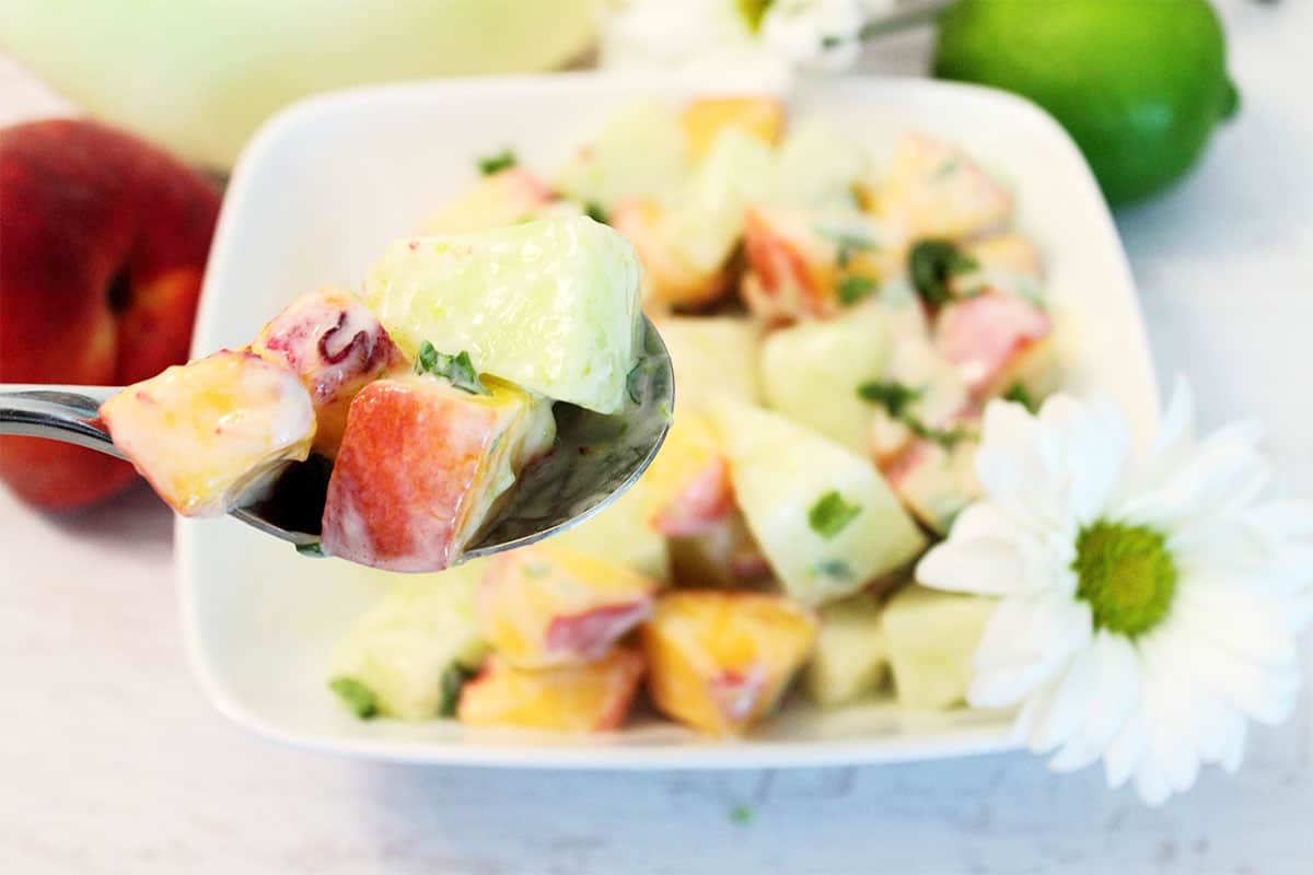 Bite of salad on a spoon over full salad bowl.