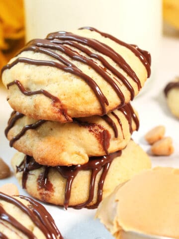 Closeup stacked cookies with spoon of peanut butter.